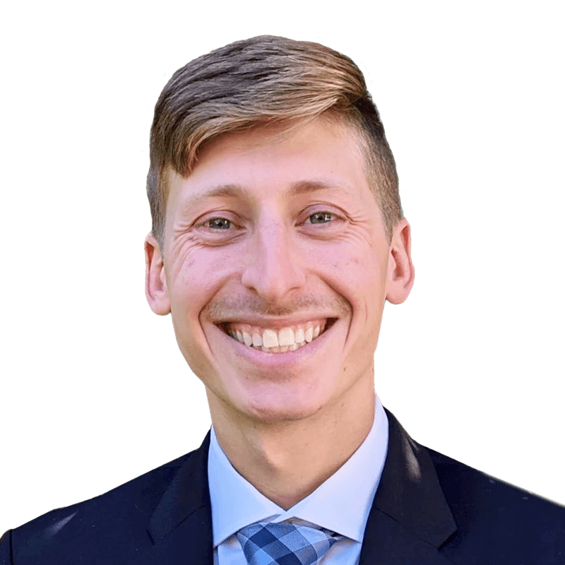 Headshot of Joshua Gilsten who is smiling and has short blond hair. He is wearing a suit and a blue checkered tie.