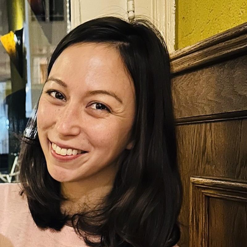 Headshot of Liz Voeller, who is smiling and tilting her head to the right. She has shoulder length brown hair.