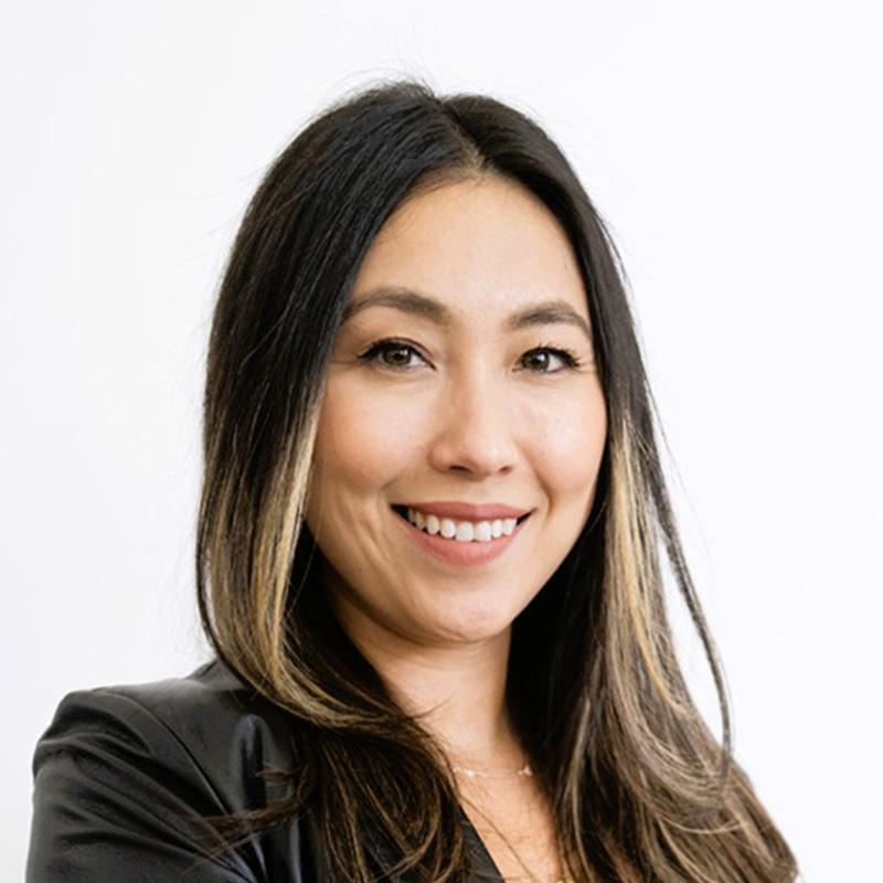 Headshot of Ashley Anderson, who is smiling and has long black hair with highlights. She wears a black leather jacket.