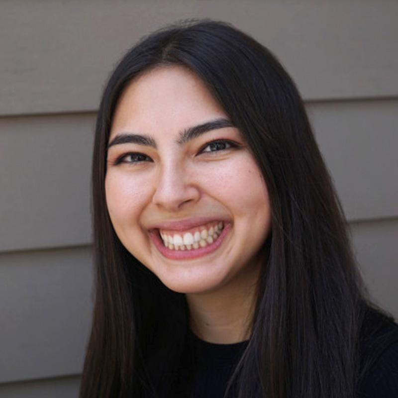 Headshot of Hannah Blumberg, who is smiling and has long straight black hair. She wears a black top.