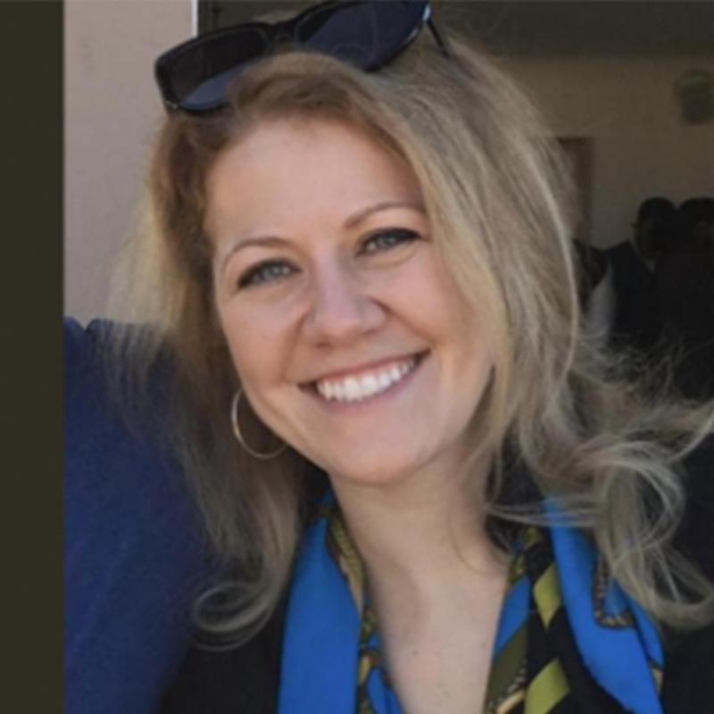 Headshot of Claire Goebel, who is smiling and wears sunglasses on her head. She has medium length blonde hair.